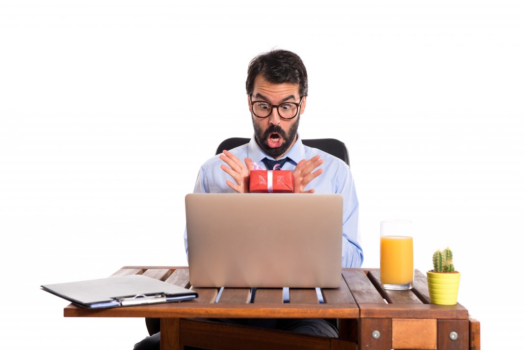 Surprised businessman in his office with gift
